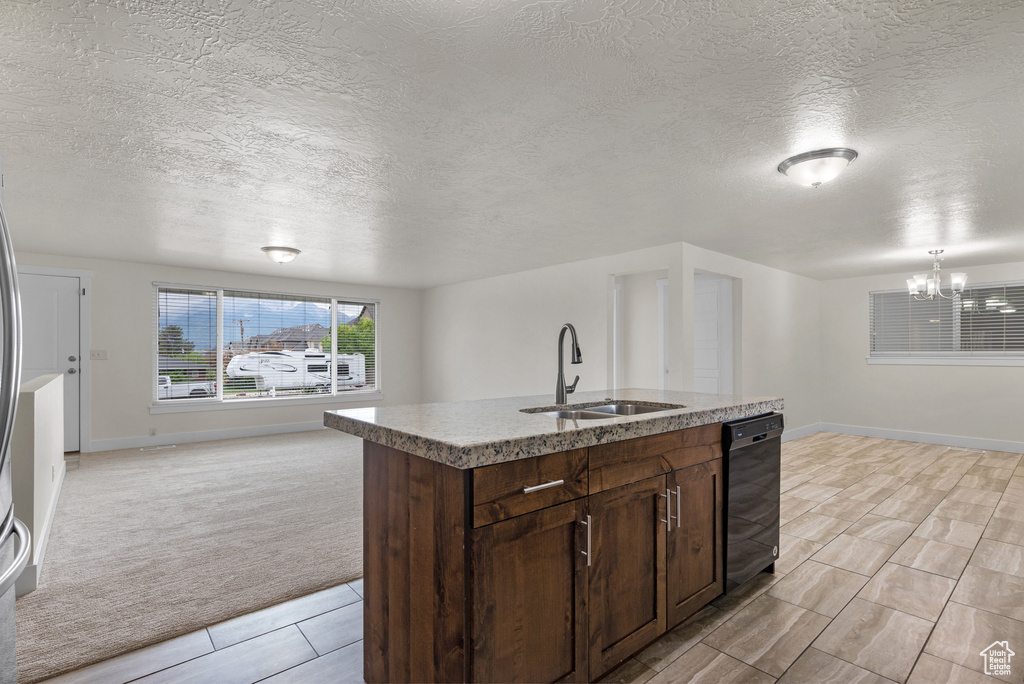 Kitchen with a sink, open floor plan, light carpet, black dishwasher, and a chandelier