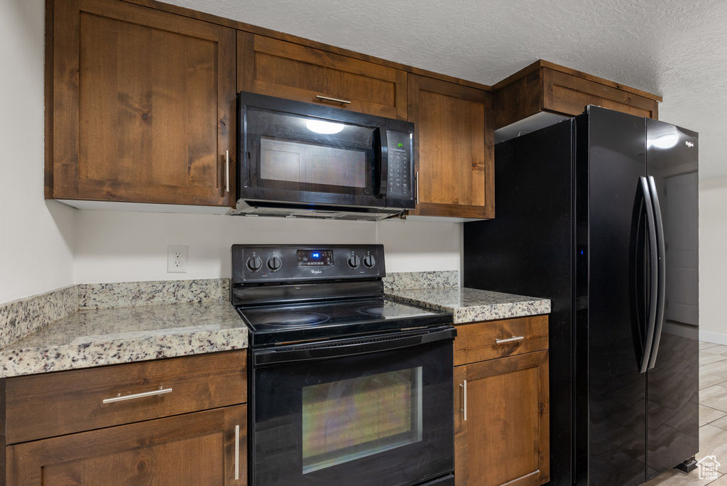 Kitchen featuring black appliances and light stone countertops