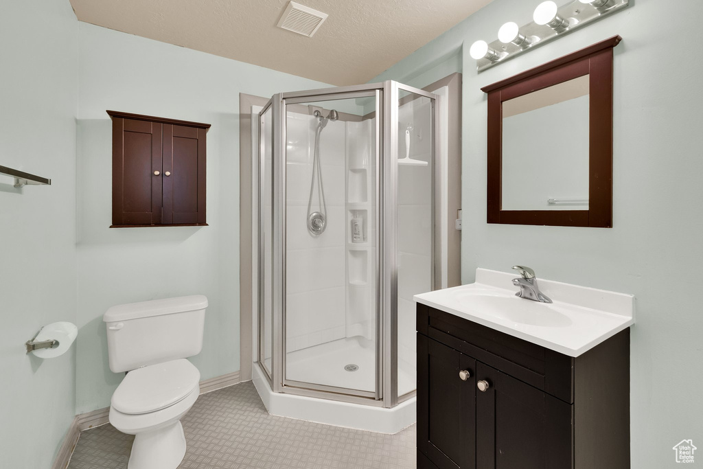 Full bath with a shower stall, vanity, baseboards, and toilet