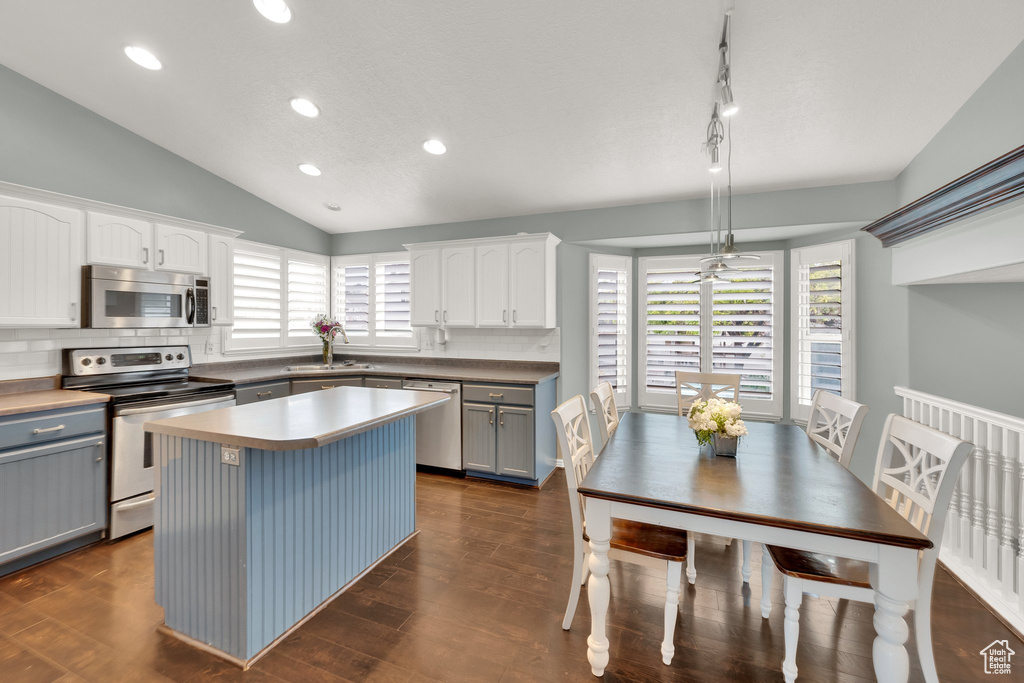 Kitchen with appliances with stainless steel finishes, gray cabinets, lofted ceiling, a sink, and backsplash
