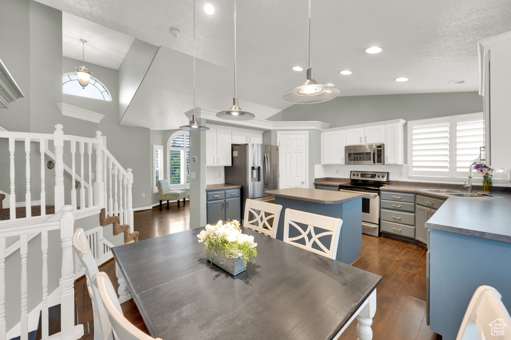 Dining area featuring dark wood-style flooring, recessed lighting, stairway, and high vaulted ceiling