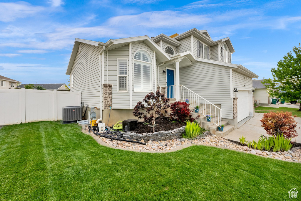 View of front of home featuring concrete driveway, cooling unit, and an attached garage