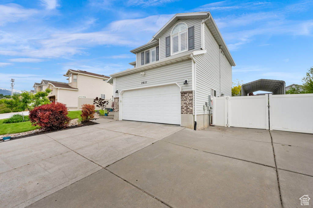 View of property exterior with concrete driveway, a carport, a gate, a garage, and fence