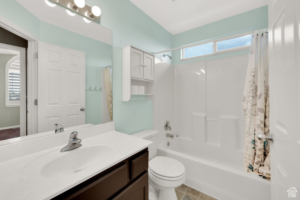 Full bath with toilet, shower / bath combo with shower curtain, and vanity