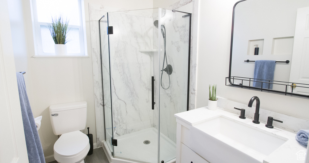 Full bath with a marble finish shower, toilet, and vanity