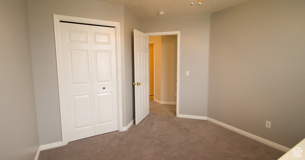 Unfurnished bedroom featuring carpet floors, a closet, and baseboards