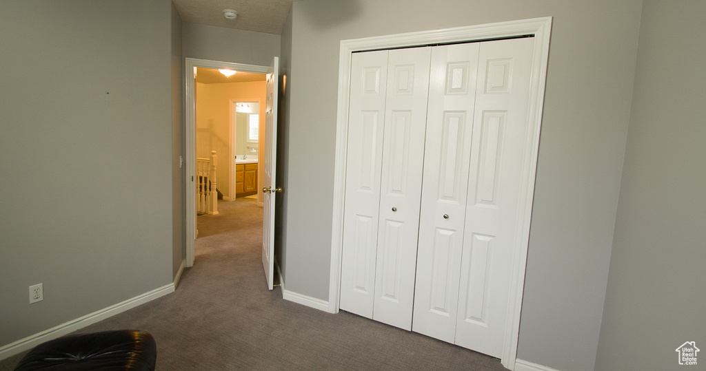 Unfurnished bedroom featuring dark carpet, baseboards, and a closet