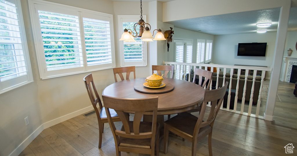 Dining area featuring healthy amount of natural light, baseboards, hardwood / wood-style floors, and a chandelier