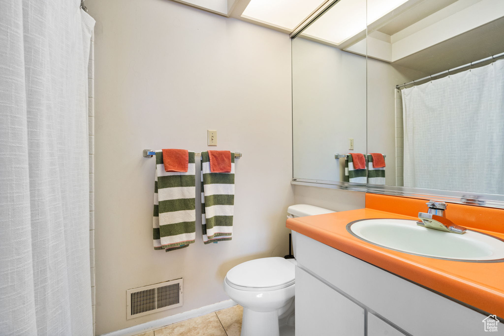 Bathroom featuring tile patterned floors, toilet, vanity, and curtained shower