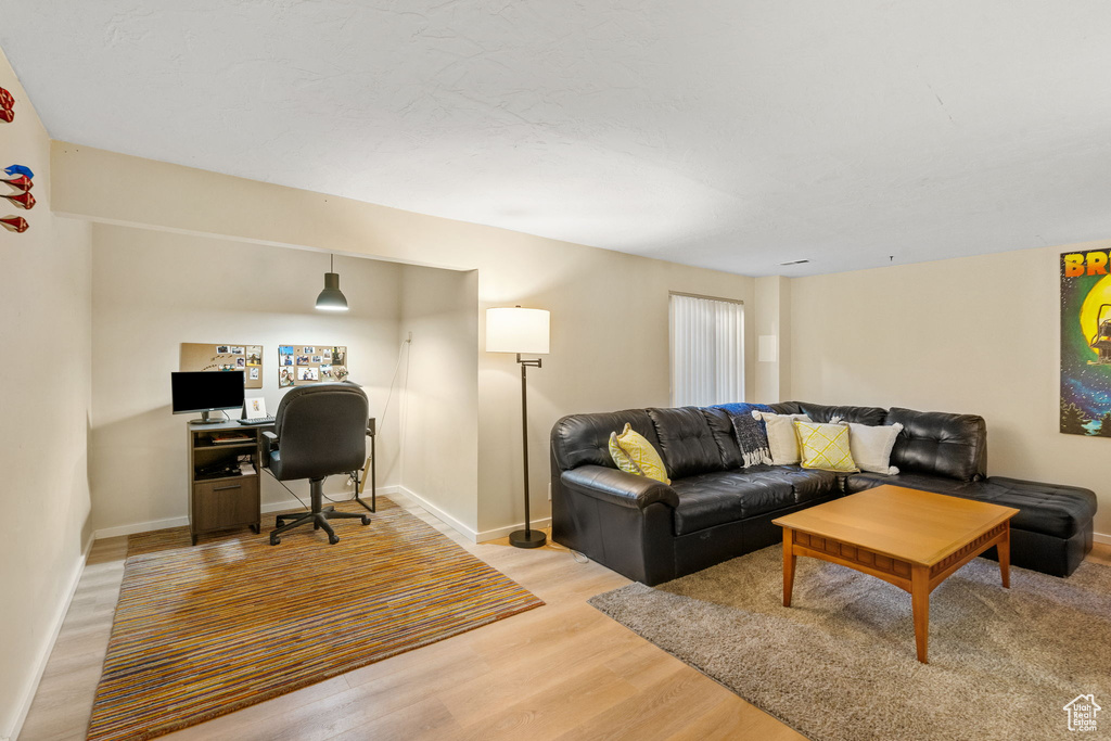 Living area featuring light wood finished floors, a desk, and baseboards