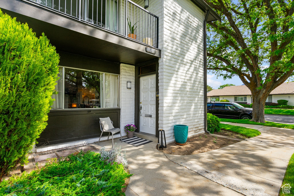 Doorway to property featuring a balcony and brick siding