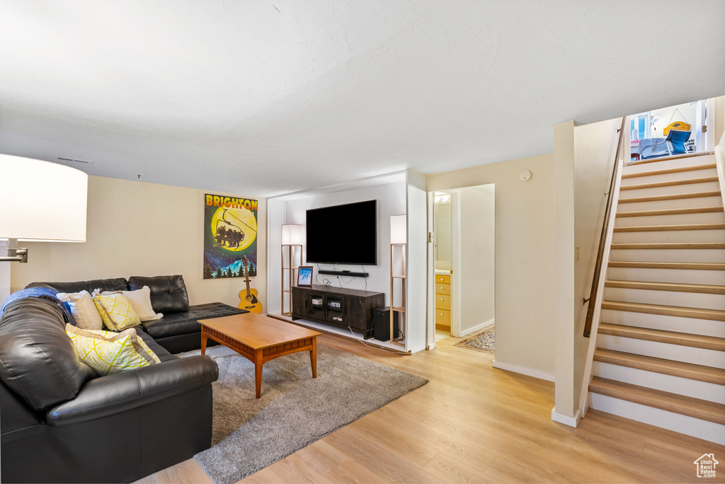 Living area with light wood-style floors, stairway, and baseboards