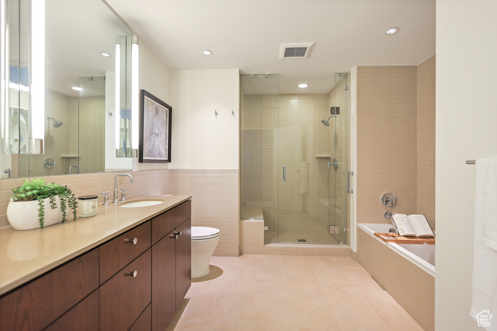 Bathroom featuring tile patterned floors, a shower stall, toilet, tile walls, and a bath