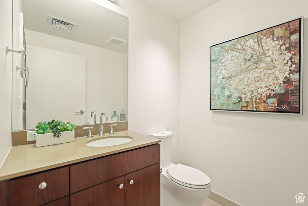 Bathroom featuring toilet, vanity, and baseboards