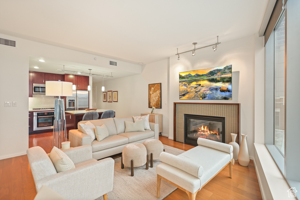 Living area featuring track lighting, light wood-style floors, a tile fireplace, and baseboards