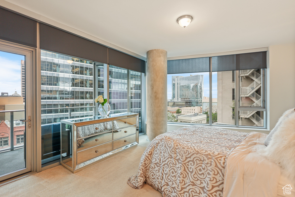 Bedroom with carpet floors, access to outside, multiple windows, and a view of city