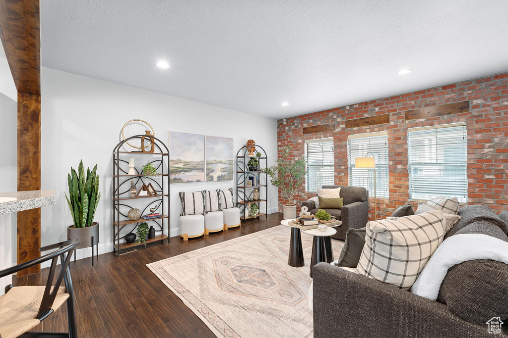 Living area with hardwood / wood-style flooring, brick wall, baseboards, and recessed lighting
