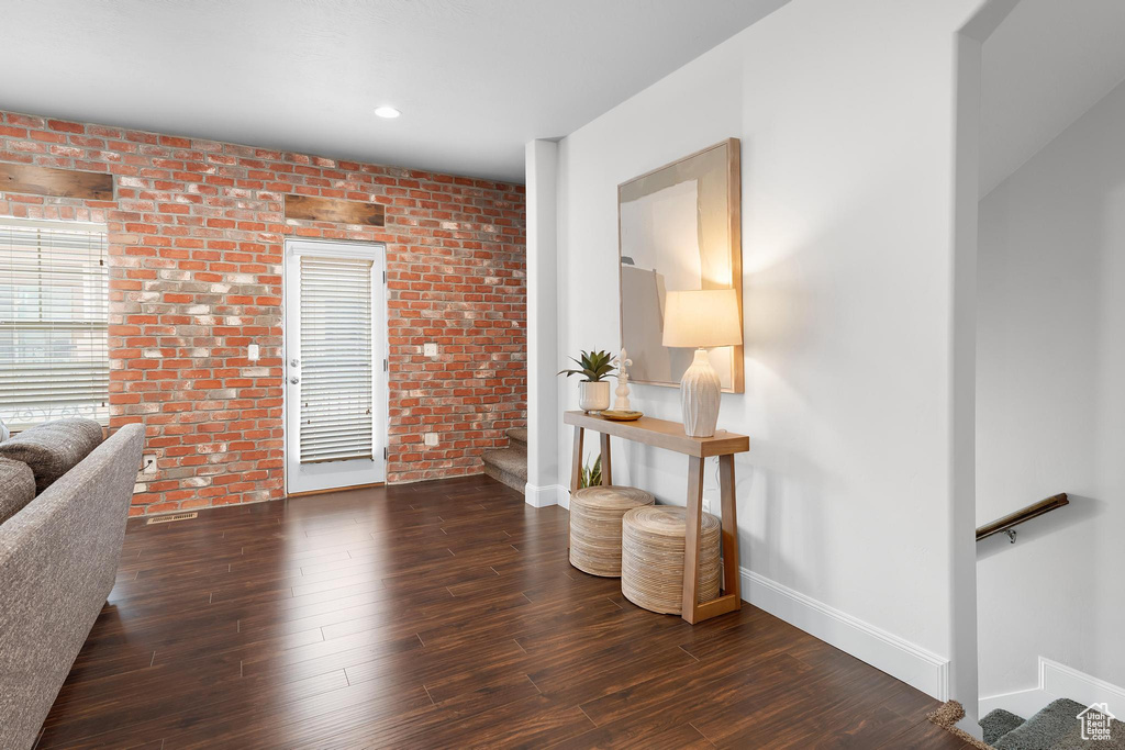 Living room with baseboards, brick wall, wood finished floors, and stairs