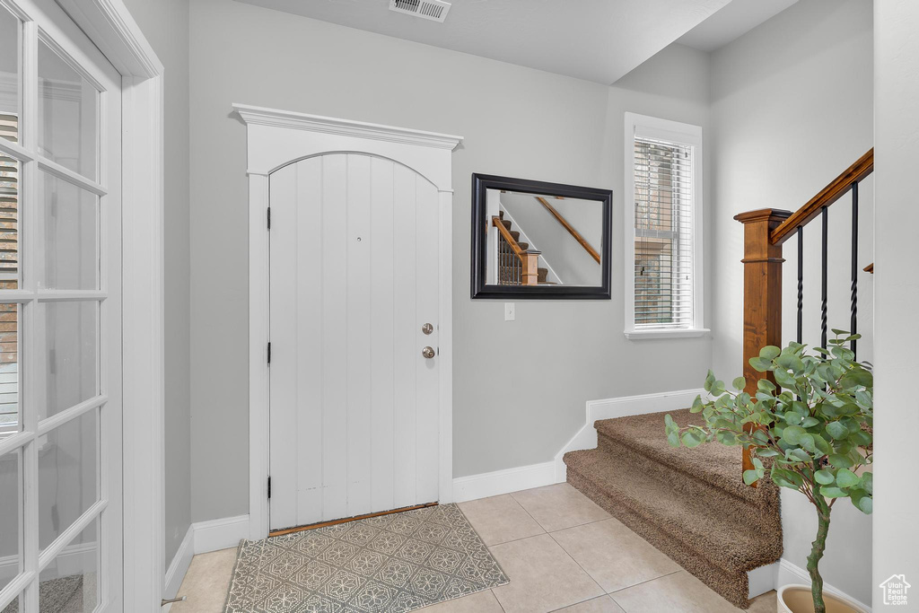 Entryway featuring stairway, baseboards, and light tile patterned floors