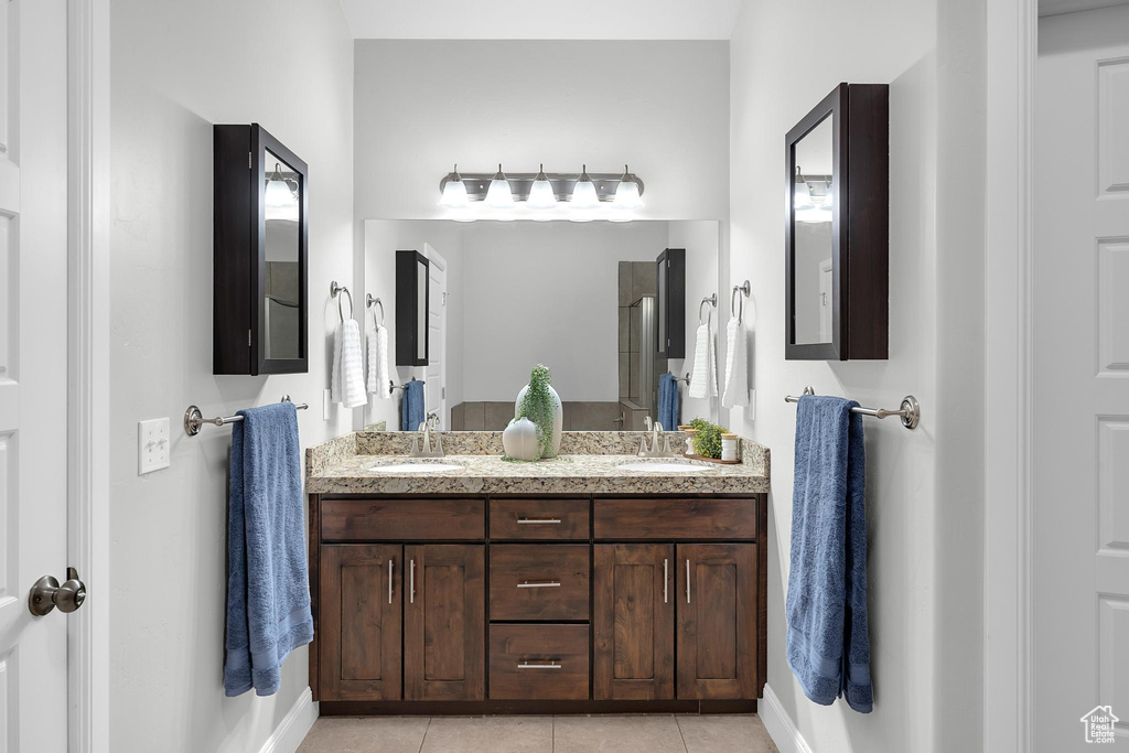 Full bathroom with double vanity, tile patterned floors, and baseboards