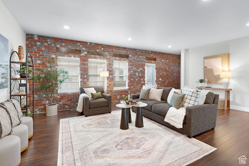 Living area with brick wall, wood finished floors, recessed lighting, and baseboards