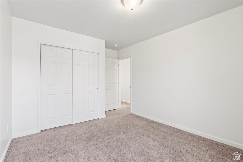 Unfurnished bedroom with carpet, baseboards, and a closet