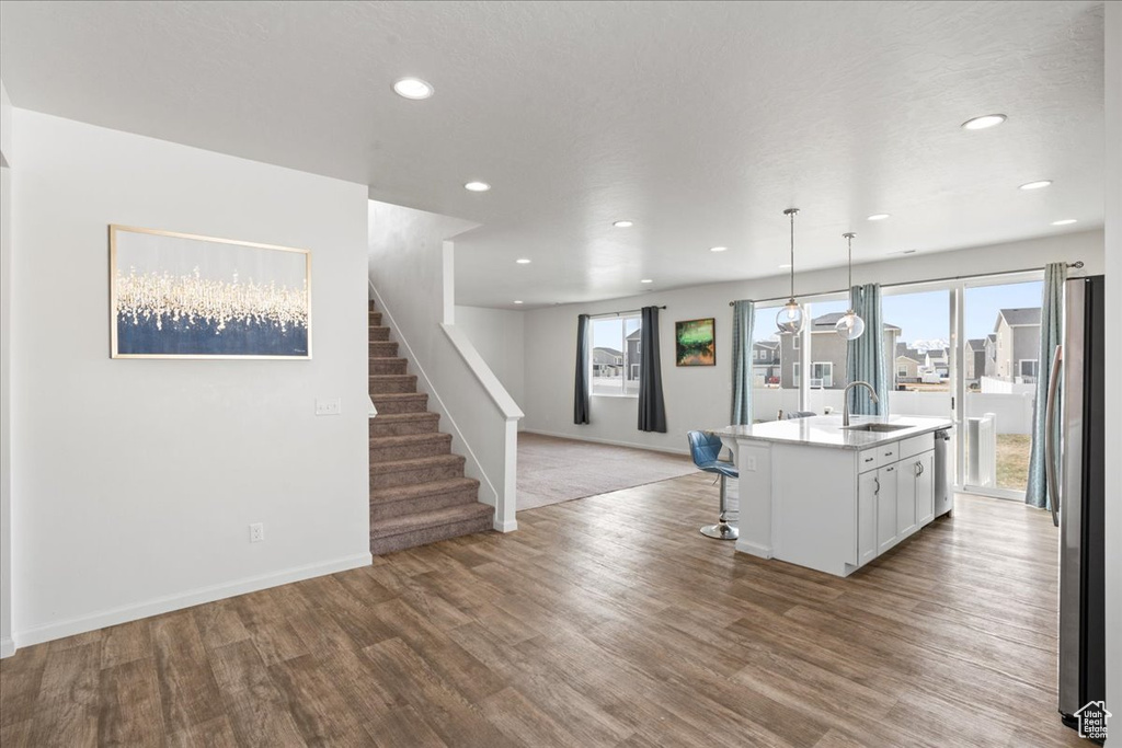 Kitchen featuring a sink, freestanding refrigerator, wood finished floors, white cabinetry, and recessed lighting