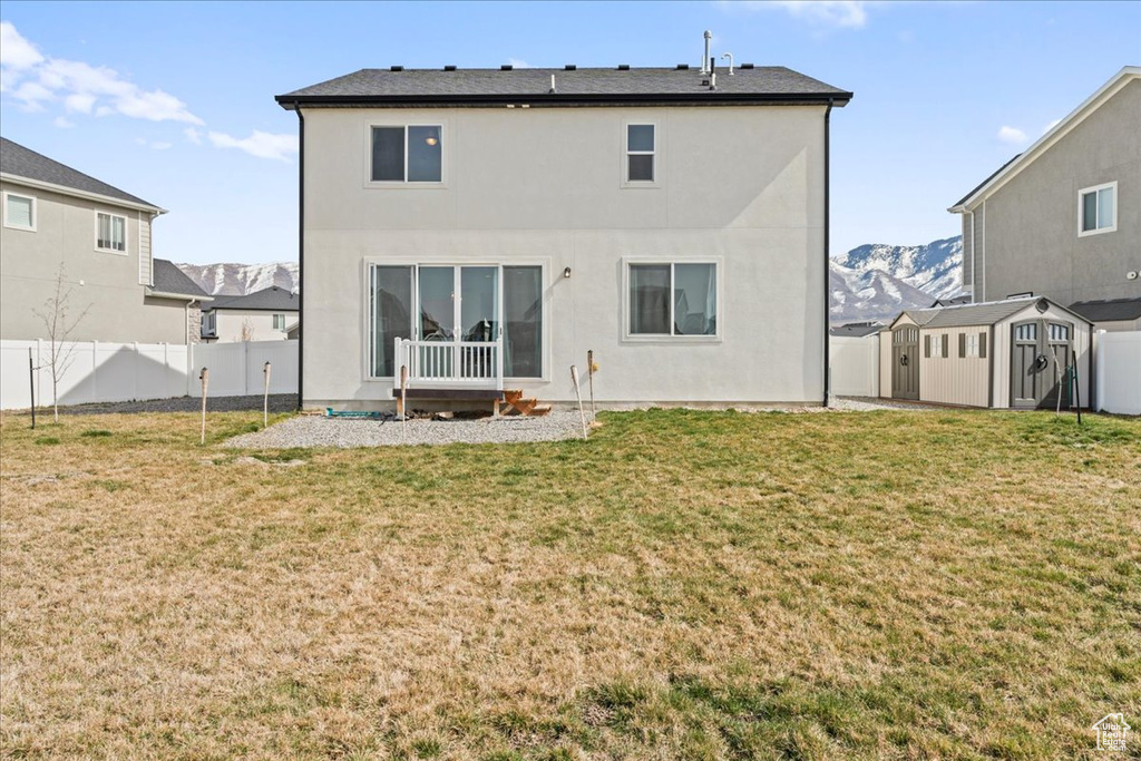 Rear view of house with a shed, an outdoor structure, stucco siding, and a mountain view