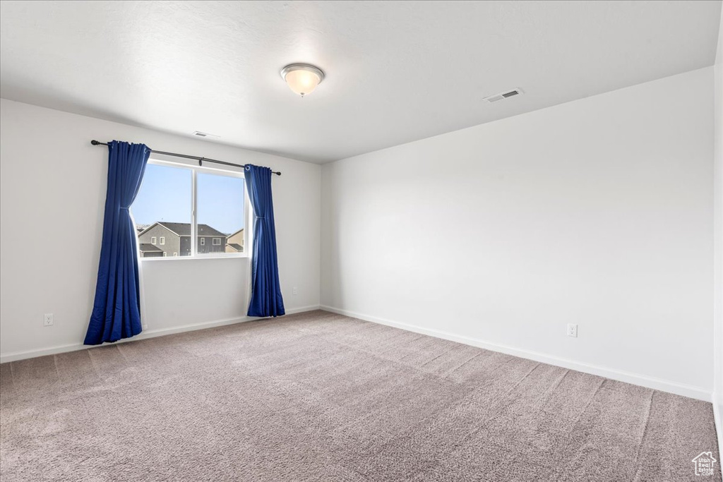Carpeted spare room featuring baseboards