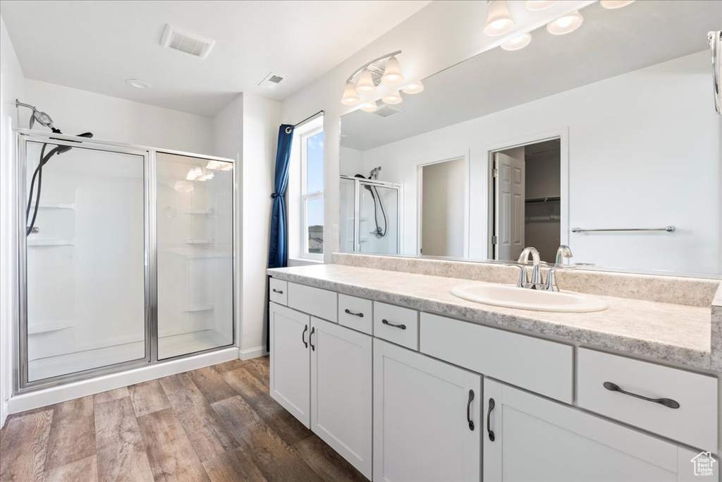 Bathroom with a stall shower, wood finished floors, and vanity