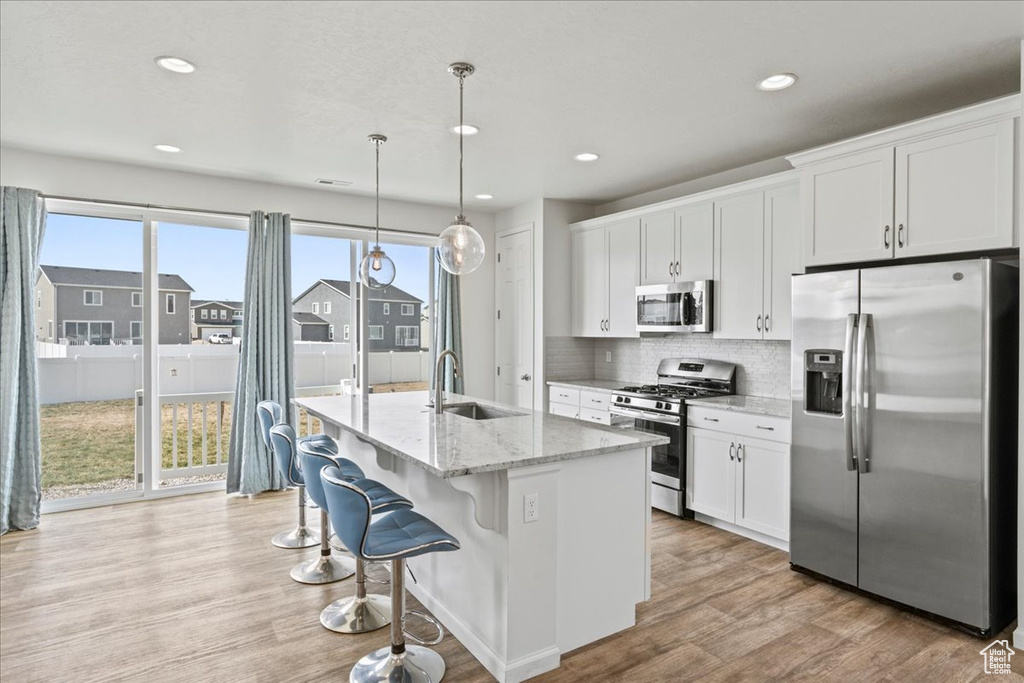 Kitchen with appliances with stainless steel finishes, a sink, white cabinets, healthy amount of natural light, and recessed lighting