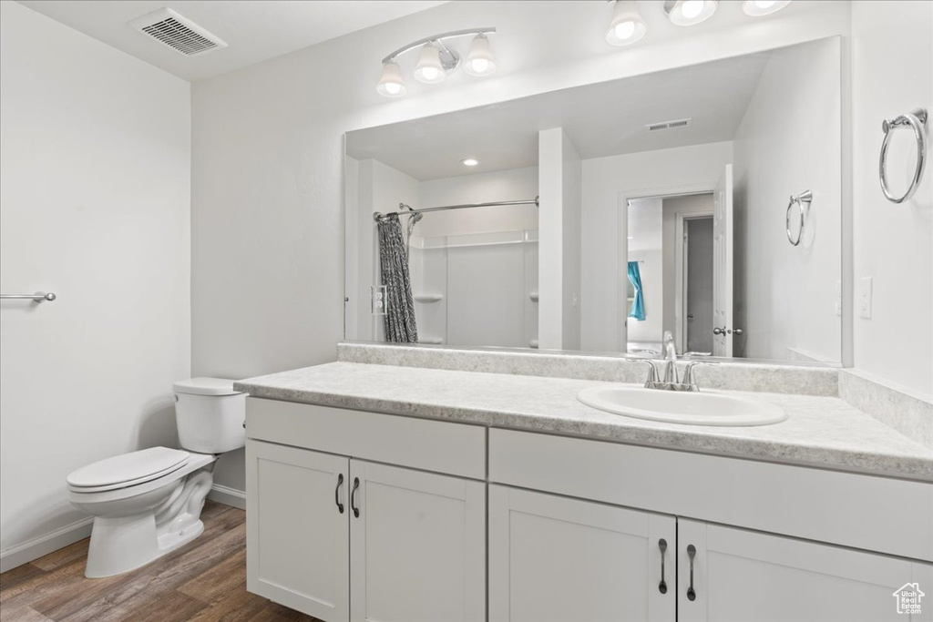Bathroom featuring toilet, wood finished floors, baseboards, a shower with curtain, and vanity
