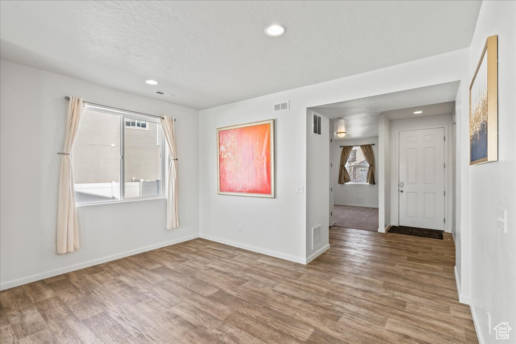 Empty room with wood finished floors, recessed lighting, baseboards, and a textured ceiling