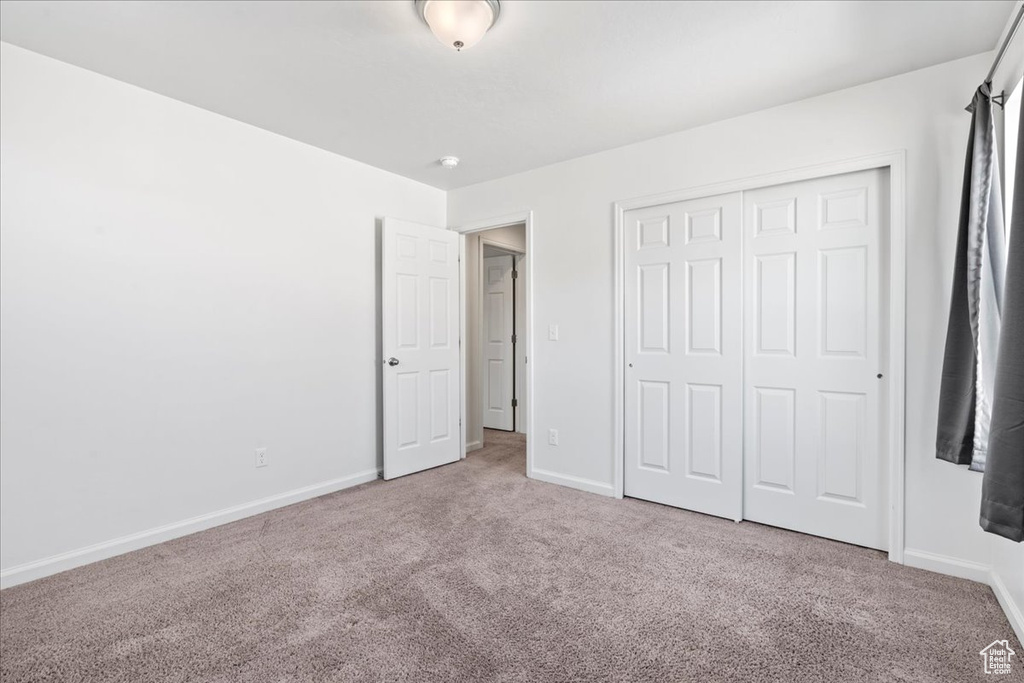Unfurnished bedroom featuring carpet, baseboards, and a closet