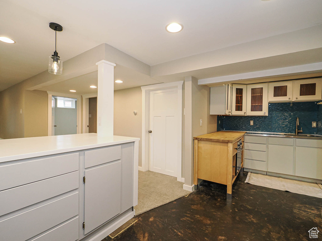 Kitchen featuring recessed lighting, glass insert cabinets, backsplash, pendant lighting, and a sink