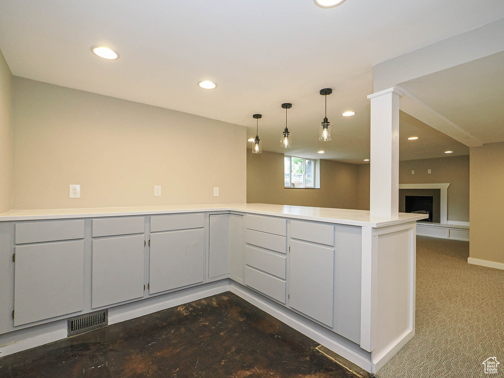 Kitchen with a peninsula, recessed lighting, light countertops, decorative light fixtures, and a fireplace with raised hearth
