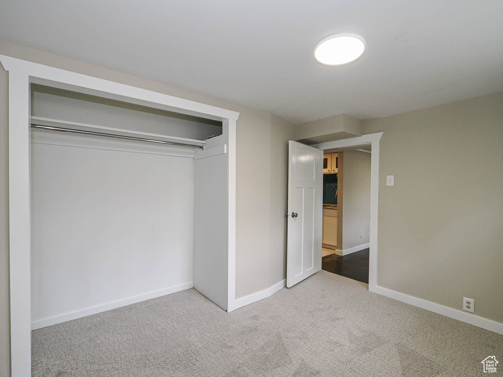 Unfurnished bedroom featuring light colored carpet, a closet, and baseboards