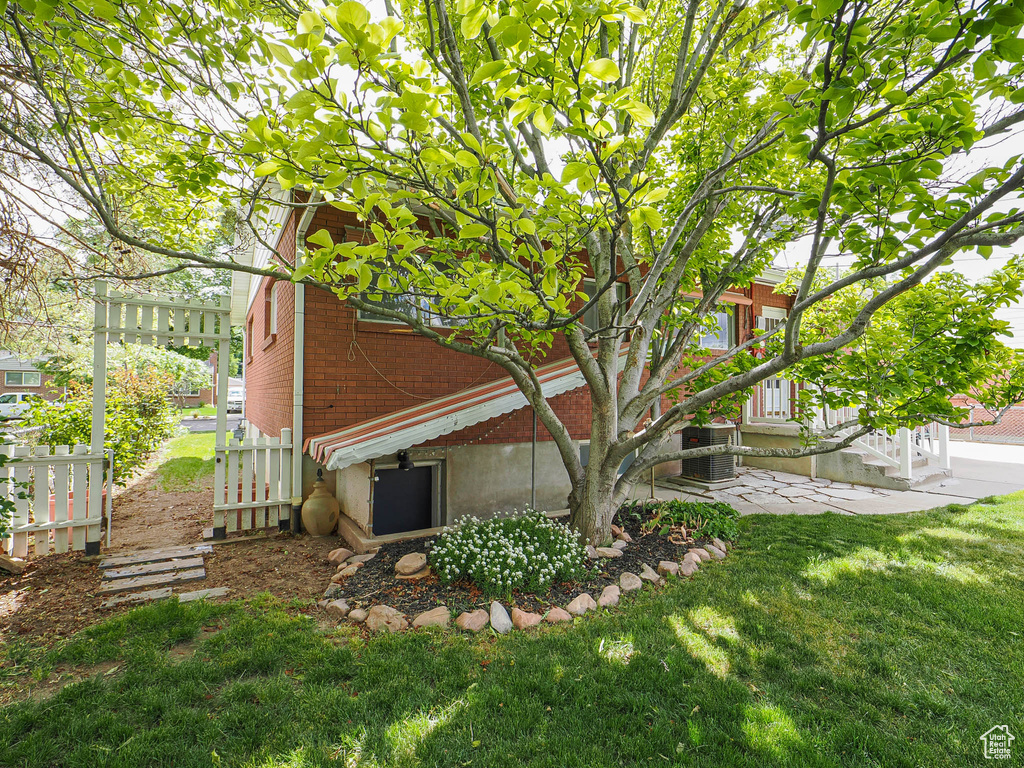 View of property exterior with brick siding, a yard, and central air condition unit