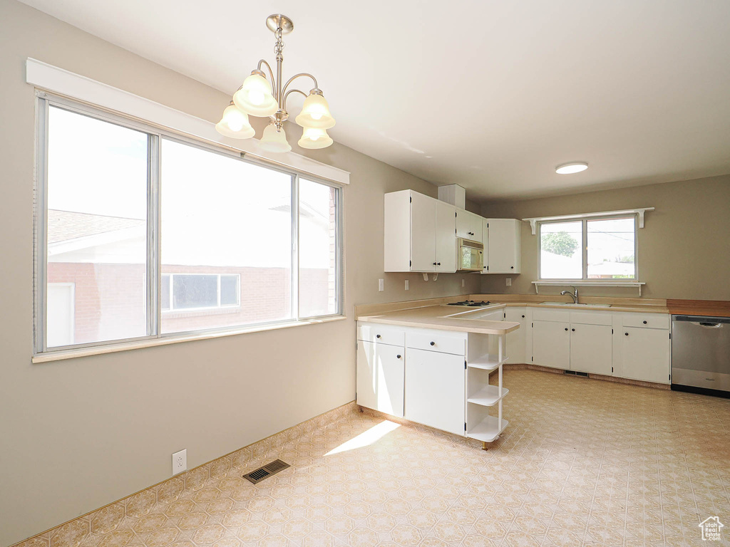 Kitchen with stainless steel dishwasher, white microwave, open shelves, a chandelier, and a sink