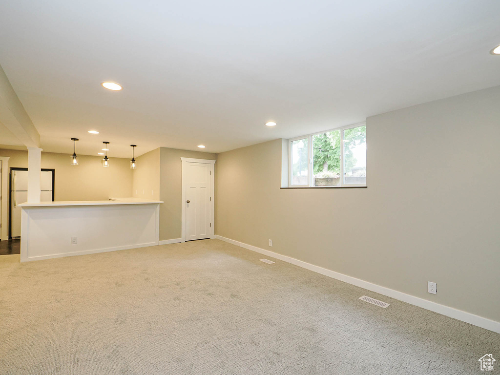 Unfurnished living room with recessed lighting, light carpet, and baseboards