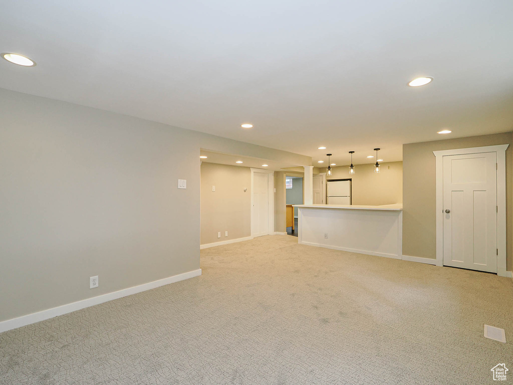 Unfurnished living room featuring recessed lighting, light carpet, and baseboards
