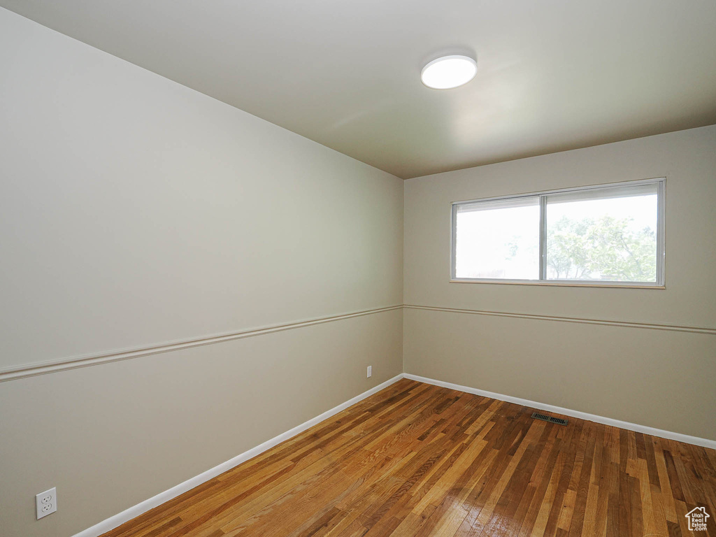 Empty room featuring baseboards and hardwood / wood-style flooring