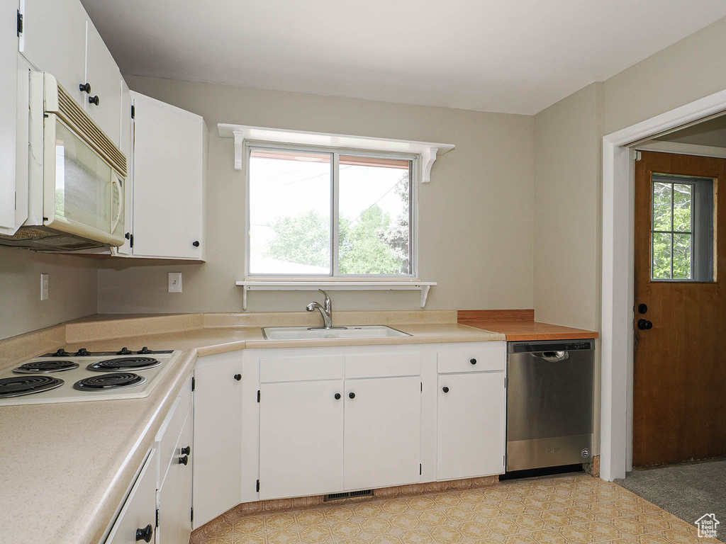 Kitchen featuring white appliances, a sink, white cabinets, and light countertops