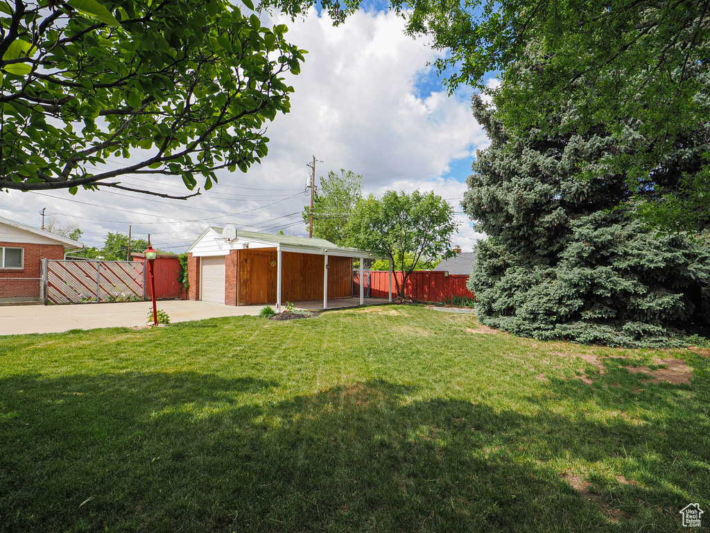 View of yard featuring concrete driveway, an outdoor structure, and an attached garage