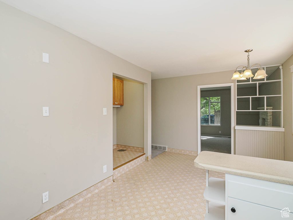 Unfurnished dining area with light carpet, a chandelier, and baseboards