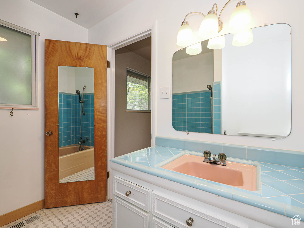 Full bath with vanity, washtub / shower combination, tile patterned floors, and baseboards