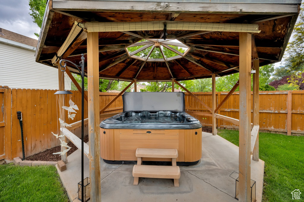 View of patio featuring a hot tub, a gazebo, and a fenced backyard