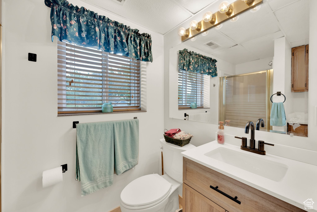 Bathroom featuring a stall shower, toilet, and vanity