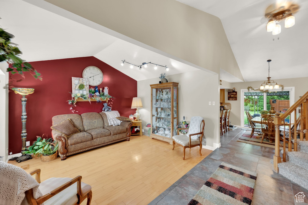 Living area featuring a chandelier, ceiling fan, baseboards, and high vaulted ceiling