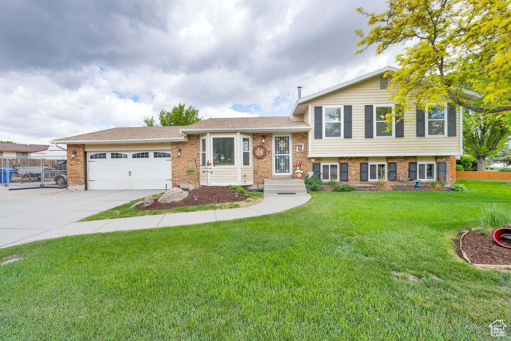 Split level home featuring brick siding, an attached garage, and concrete driveway